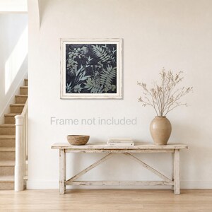 May include: A square wall art print featuring a dark charcoal background with light gray botanical leaf and fern silhouettes. The artwork is encased in a white wooden frame and displays a detailed arrangement of various plant foliage patterns.