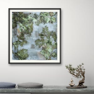 May include: A square art print featuring a botanical composition of pressed green leaves and foliage arranged on a light, textured background. The print is displayed within a thin black frame, showcasing organic shapes and natural green tones.