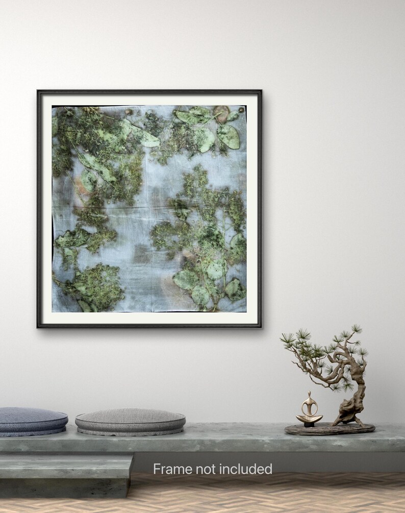 May include: A square art print featuring a botanical composition of pressed green leaves and foliage arranged on a light, textured background. The print is displayed within a thin black frame, showcasing organic shapes and natural green tones.