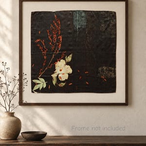 May include: A square wall art piece featuring a dark black background with a botanical print of a white flower and red foliage. The artwork is displayed within a simple dark brown frame, showcasing a clean composition with subtle textures.