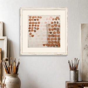 K&ouml;nnte beinhalten: Ein quadratisches gerahmtes Wandbild mit einer gitterartigen Anordnung kleiner, getrockneter, herzf&ouml;rmiger Bl&auml;tter in Braun-, Beige- und ged&auml;mpften Oranget&ouml;nen auf cremefarbenem Hintergrund mit einem wei&szlig;en, abgenutzten Holzrahmen.