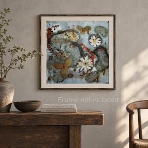 May include: A square wall art print featuring a botanical composition of pressed white flowers, green lily pads, and reddish-orange foliage on a light blue background, enclosed in a dark wood frame. The text Frame not included is visible.