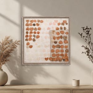 K&ouml;nnte beinhalten: Ein quadratisches Wandbild mit einem Raster aus gepressten, getrockneten Bl&auml;ttern in Orange-, Braun- und Cremet&ouml;nen. Die Bl&auml;tter sind in einem strukturierten Muster auf hellem Hintergrund angeordnet und von einem d&uuml;nnen, hellen Holzrahmen umgeben.