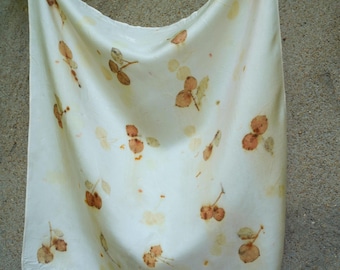 Puede incluir: Un pañuelo cuadrado de tela color blanco roto con un estampado botánico disperso de pequeñas formas y tallos marrones que recuerdan a hojas. La tela tiene una superficie lisa y ligeramente reflectante, drapeada con pliegues visibles.