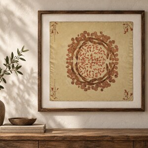 Pu&ograve; includere: Un'opera d'arte da parete quadrata incorniciata con uno sfondo in tessuto beige chiaro e una stampa botanica circolare centrale. Il design &egrave; composto da foglie e baccelli bruno-rossastri disposti in modo simmetrico, con piccoli rametti negli angoli.