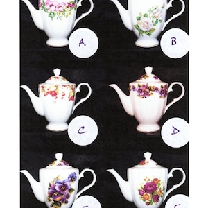 Puede incluir: Colección de seis teteras de porcelana blanca, cada una con un diseño floral diferente. Las teteras tienen una forma clásica con boquilla, asa y tapa. Los diseños florales incluyen rosas, violetas y otras flores coloridas. Cada tetera está etiquetada con una letra.