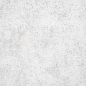 Peut inclure: Gros plan sur une surface en béton blanc avec une texture mouchetée. La surface présente un motif subtil et irrégulier de taches gris clair et blanches.