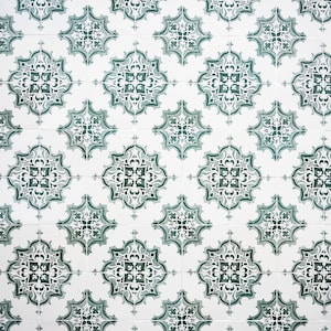 Op de afbeelding: Een witte betegelde muur met een herhalend patroon van groene en witte bloemenmotieven. De tegels zijn in een rasterpatroon gerangschikt.