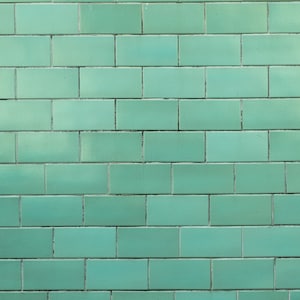 May include: A wall covered in light green tiles. The tiles are arranged in a brick pattern.