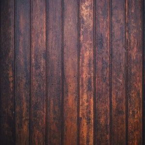 Könnte beinhalten: Eine Nahaufnahme einer dunkelbraunen Holzverkleidungswand mit vertikalen Brettern. Das Holz hat einen rustikalen, verwitterten Look mit einer leicht unebenen Oberfläche.