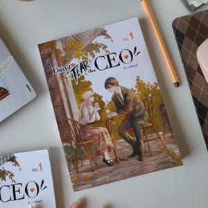 May include: A book titled "Don't Fear the CEO Vol. 1" by P.J. Reed. The cover art depicts a couple at a cafe table. The book is white with black text and a heart symbol. Another copy of the book is visible in the image.