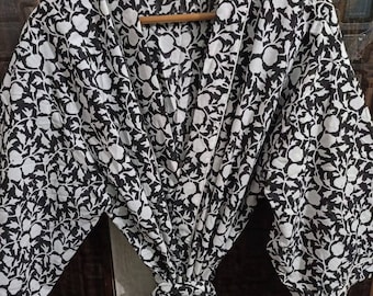 May include: A black and white floral print robe with a tie belt and pockets. The robe has a traditional Japanese kimono style.
