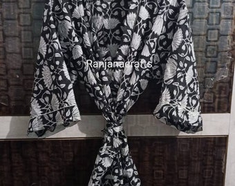 May include: Black and white floral print cotton robe with a tie waist. The robe has long sleeves and a shawl collar. The text "Ranjanacrafts" is printed on the front of the robe.