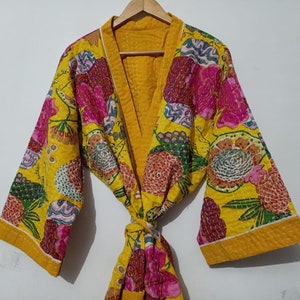 May include: A yellow floral quilted robe with a pink and green floral pattern. The robe has a tie closure and long sleeves.