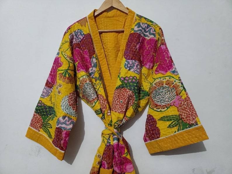 May include: A yellow floral quilted robe with a pink and green floral pattern. The robe has a tie closure and long sleeves.