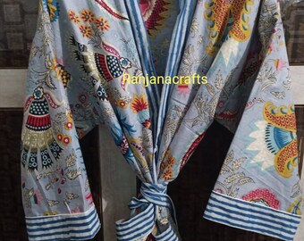 Puede incluir: Una bata de algodón azul claro con estampado floral colorido y ribetes a rayas azules y blancas. La bata tiene un cinturón de atar y mangas largas.