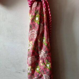 May include: A pink and white floral patterned fabric with a red and white striped fabric tied around it.