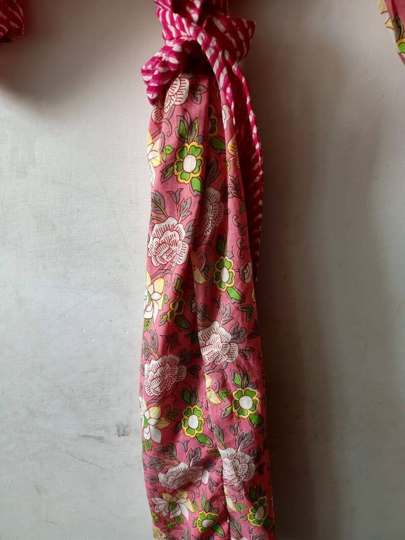 May include: A pink and white floral patterned fabric with a red and white striped fabric tied around it.