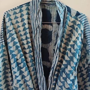 Könnte beinhalten: Eine blaue und weiße gemusterte Robe mit einem gestreiften Kragen. Die Robe ist aus einem leichten Stoff gefertigt und hat eine lockere Passform.