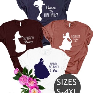 May include: Four different t-shirts featuring Disney princesses with humorous sayings. The shirts are in various colors, including white, navy blue, maroon, and light brown. The text on the shirts includes "Under the Influence", "Drinking Beauty", "Drunkest of Them All", and "Bibbidi Bobbidi I Do". The shirts are available in sizes S-4XL.
