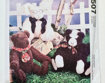 Könnte beinhalten: Ein Schnittmuster zum Nähen von drei Stofftieren: einem braunen Bären, einem weißen Kaninchen mit Brille und einem schwarz-weißen Hund. Das Schnittmuster ist von McCall's Crafts und trägt den Titel "Little City Bears & Co. designs by Maureen Hills".
