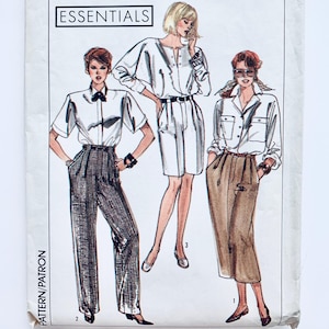 Puede incluir: Patrón de costura Simplicity Essentials para tres blusas diferentes. El patrón es para las tallas Y (18-20-22) y EUR. Y (46-48-50). El patrón muestra a tres mujeres usando las blusas. La primera mujer lleva una blusa blanca con un cinturón marrón y pantalones marrones. La segunda mujer lleva una blusa blanca con un cinturón marrón y una falda marrón. La tercera mujer lleva una blusa blanca con un cinturón marrón y una falda marrón.