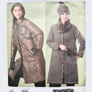 May include: A Vogue Patterns sewing pattern envelope V2868 by Koos van den Akker featuring two long coats. The left coat is bronze with a dark paisley pattern and black trim. The right coat is grey with a matching hat and scarf, featuring button closures.