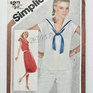 Op de afbeelding: Simplicity naaipatroon envelop met een wit topje en een blauwe matrozenkraag, en een rode jurk met een witte kraag. Op de envelop staat de tekst "Simplicity" en "$2,75".