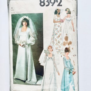 Peut inclure: Patron de couture vintage Simplicity n° 8392 pour une robe de mariée et deux autres robes. Le patron est pour les tailles 14, 5 et 4. La robe de mariée est blanche avec des manches longues et un décolleté carré. Les deux autres robes sont fleuries et bleues.