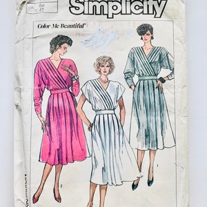 Könnte beinhalten: Simplicity Schnittmuster Nummer 7278, "Color Me Beautiful", für ein Wickelkleid mit langen oder kurzen Ärmeln. Das Schnittmuster zeigt drei verschiedene Versionen des Kleides in Pink, Weiß und Schwarz-Weiß-Streifen.
