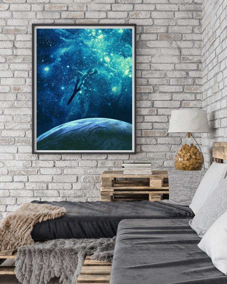 May include: A framed print of a blue and green galaxy with a silhouette of a person jumping towards the Earth. The Earth is a blue and green sphere with a white cloud cover.