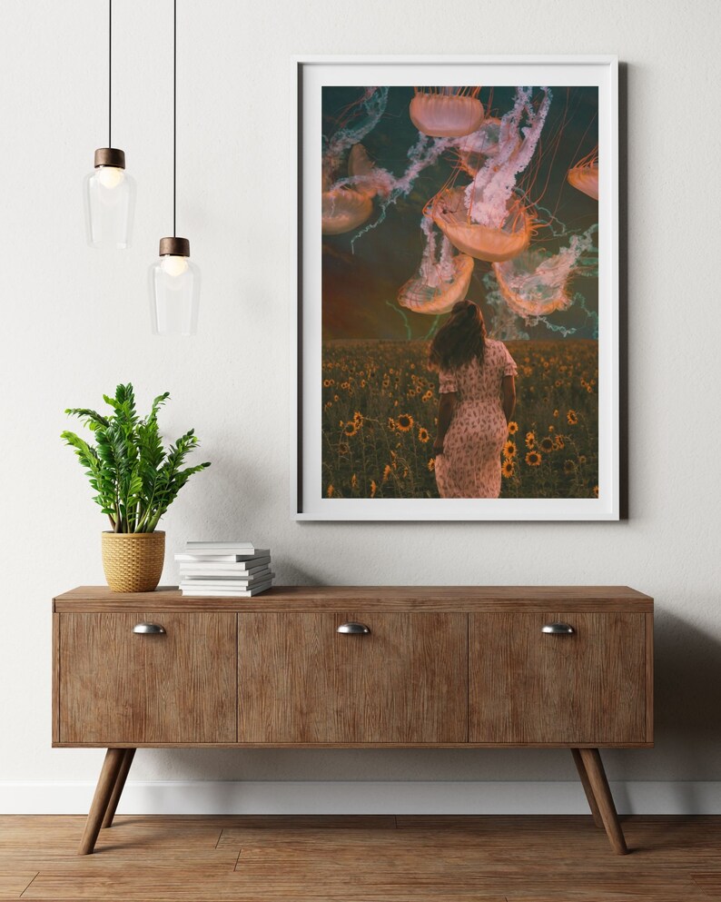 May include: A woman in a white dress walks through a field of sunflowers, looking up at a sky filled with jellyfish.