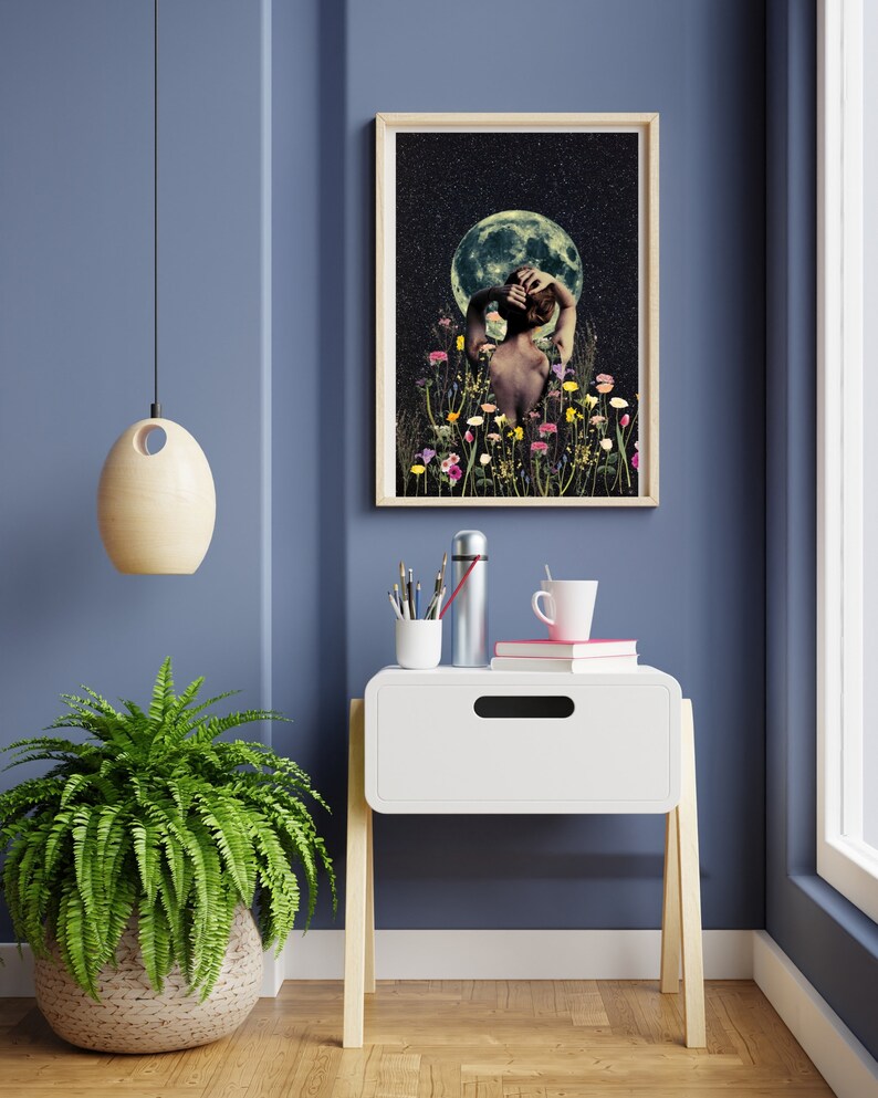 May include: A framed print of a woman standing in a field of flowers with a full moon in the background. The woman is facing away from the viewer and has her hair pulled back. The moon is a light blue color and the flowers are a variety of colors.
