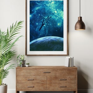 May include: A framed print of a person diving into a blue and green galaxy with stars. The print is hanging on a white wall above a wooden dresser with three drawers.
