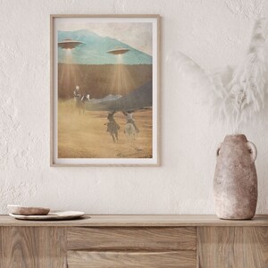 Puede incluir: Una impresi&oacute;n enmarcada de una ilustraci&oacute;n de estilo vintage que representa a tres vaqueros montando a caballo a trav&eacute;s de un paisaje des&eacute;rtico con tres platillos voladores en el cielo arriba.