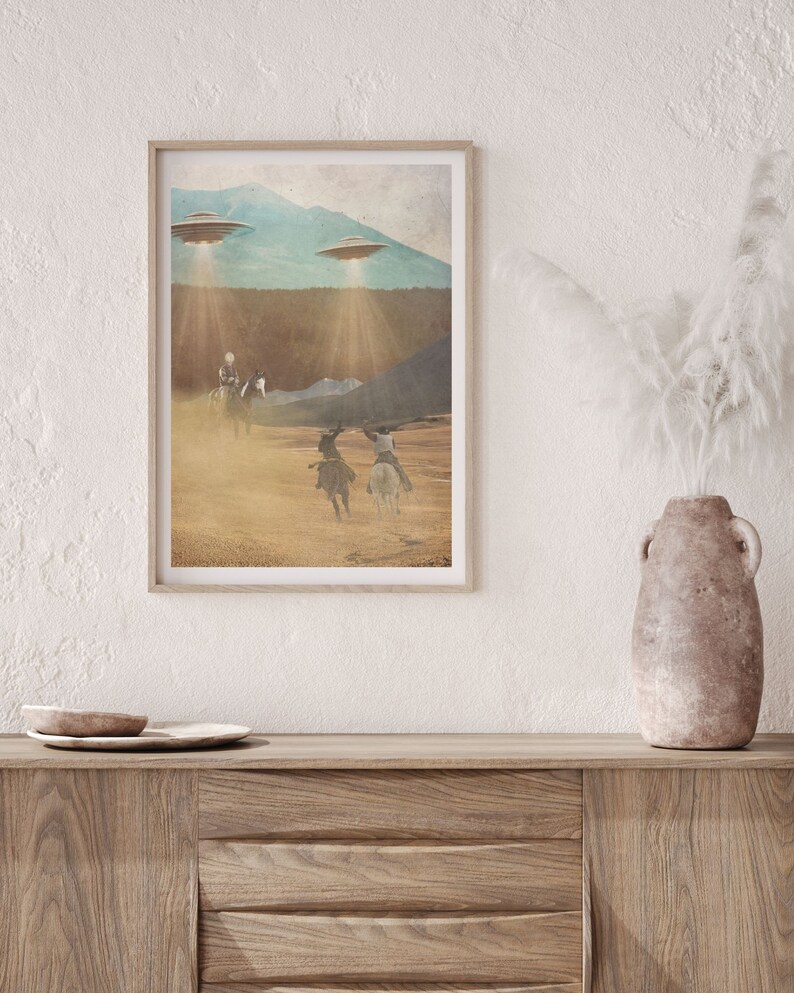 Puede incluir: Una impresi&oacute;n enmarcada de una ilustraci&oacute;n de estilo vintage que representa a tres vaqueros montando a caballo a trav&eacute;s de un paisaje des&eacute;rtico con tres platillos voladores en el cielo arriba.