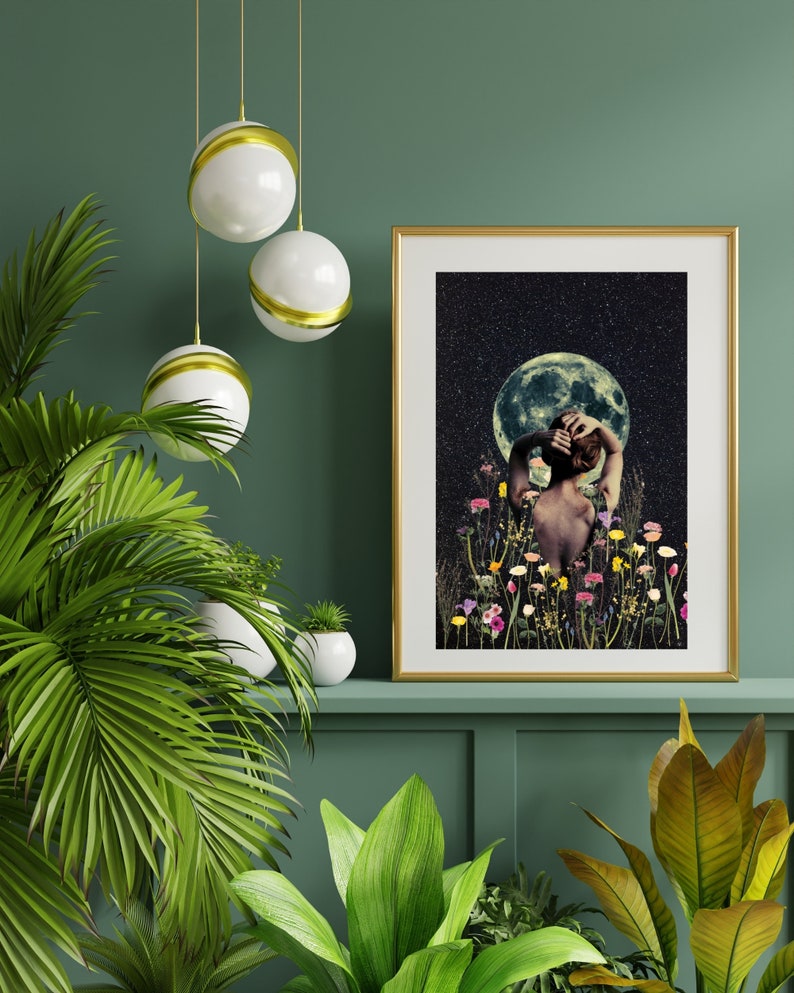 May include: A gold framed print with a woman standing in a field of flowers with a full moon and stars in the background.
