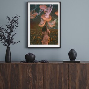 May include: A framed print of a woman walking through a field of sunflowers with jellyfish floating above her. The jellyfish are a pale orange color and the sky is a dark blue with clouds.