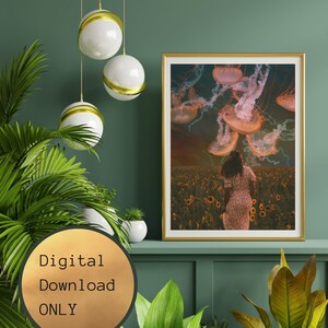 May include: A digital download print of a woman walking through a field of sunflowers with jellyfish floating in the sky above her. The print has a gold frame and is hanging on a green wall.