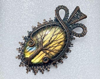May include: A handcrafted pendant featuring a large, oval-shaped gemstone with yellow and blue hues, intricately wrapped in copper wire. The wirework forms a tree design and a decorative bail, creating a unique, nature-inspired jewelry piece.