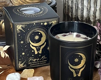 May include: A black candle in a glass jar with a label featuring a crescent moon and star design. The candle is next to a matching box with gold accents and the text "Purifying Moon Palo Santo & Lavender Manifestation Candles". Crystals and dried lavender are scattered around.