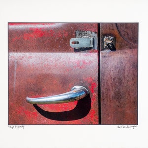 May include: A close-up of a rusty red truck door with a chrome door handle and a metal latch. The text "High Security" is written below the image.