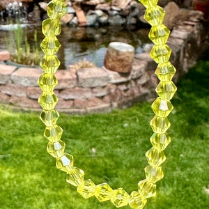 May include: A yellow crystal bracelet with faceted beads. The bracelet is made of clear glass beads with a yellow tint.