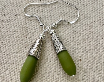 Pode incluir: Um par de brincos de gota verde oliva com detalhes em filigrana prateada.