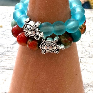 May include: Two bracelets with turquoise and red beads and silver turtle charms.