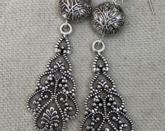 Peut inclure: Une paire de boucles d'oreilles pendantes en argent avec un motif de filigrane et une perle ronde texturée en haut.