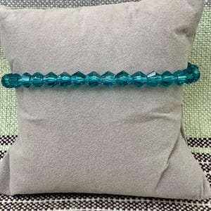 May include: A teal blue glass beaded bracelet with faceted beads.