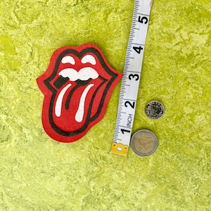 May include: Red and black tongue and lips patch with white details. The patch is about 2 inches wide.