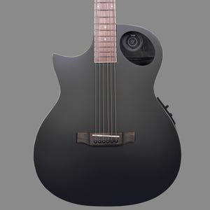 Pode incluir: Um violão preto com um furo sonoro no lado. O violão tem uma ponte de madeira e um acabamento preto.