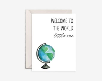 Puede incluir: Una tarjeta de felicitación blanca con una ilustración en acuarela de un globo terráqueo azul y verde sobre un soporte negro. El texto impreso en tinta negra dice: WELCOME TO THE WORLD little one. La tarjeta está frente a un sobre beige claro.